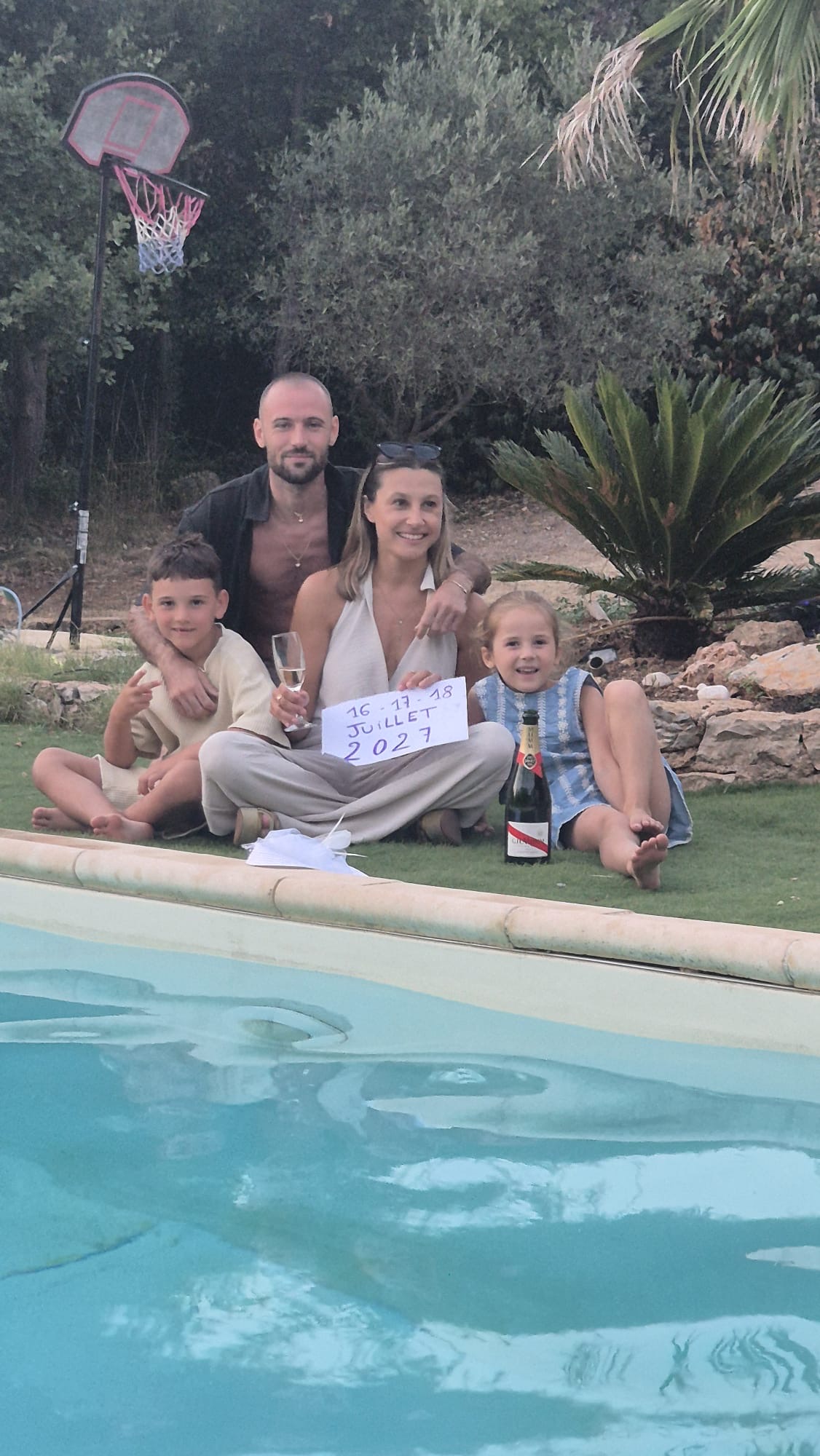 La famille réunie avec la pancarte 16-17-18 juillet 2027